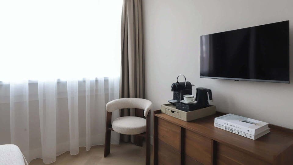 Corner setup with smart TV, Nespresso machine and a stylish chair — everything you need for a quiet moment in.