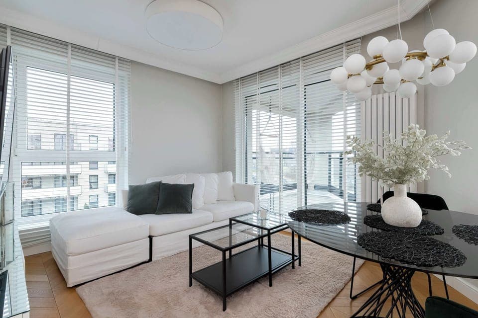 Bright living room with comfortable sofa, large windows, elegant furniture, and soft neutral tones creating a calm atmosphere.