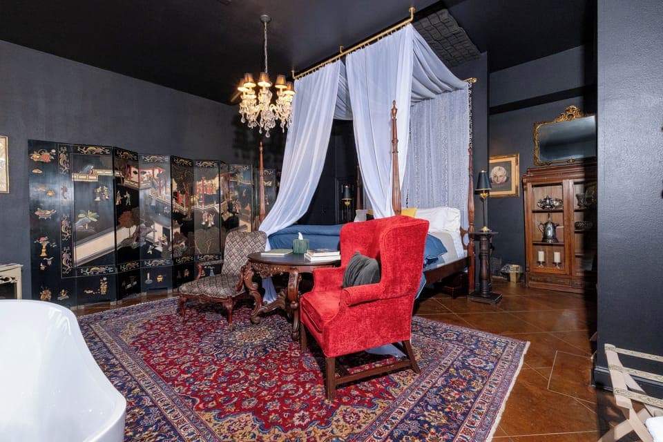 Four-poster canopy bed and seating area set beneath a crystal chandelier.