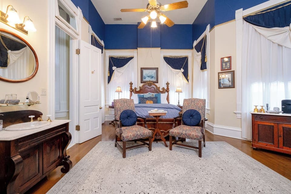View toward the sleeping area, highlighting the room’s high ceilings, blue accent walls, and seating nook.