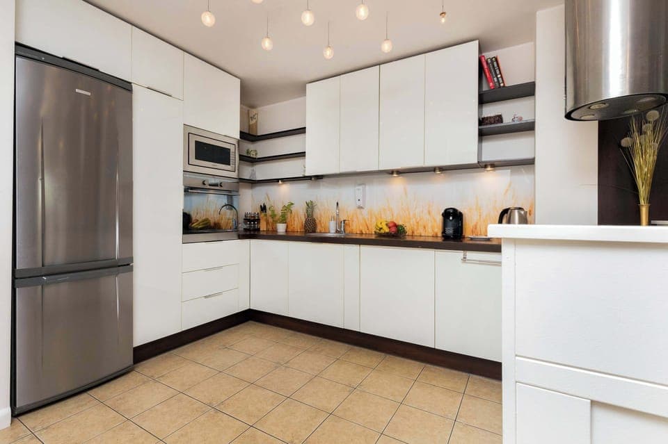 A modern kitchen with white cabinets and built-in appliances. The layout is spacious and functional for cooking.