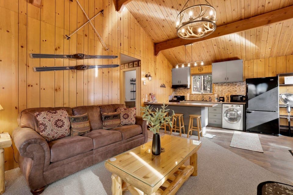 Cozy mountain living room with a stone fireplace, comfy seating, and smart TV—perfect for relaxing evenings, movie nights, and warm cabin vibes after outdoor adventures.