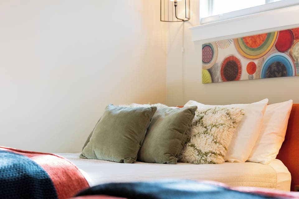 Plush pillows, soft textures and vibrant artwork create a cozy retreat.