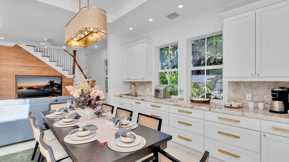 Your bright, modern kitchen flows seamlessly into the dining area, where you'll enjoy meals at the elegant table surrounded by lush garden views.