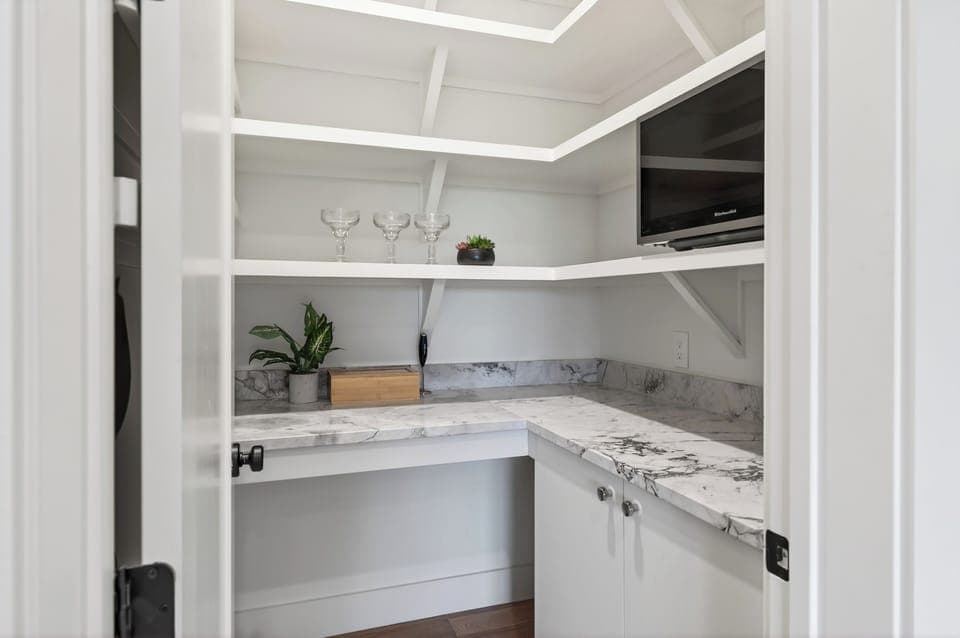 Walk-in pantry with marble counters and extra storage.