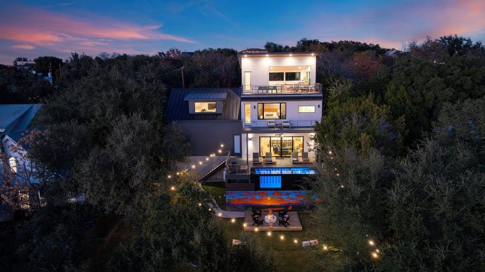 Austin nights shine at this multi-level retreat, with glowing decks, a private pool, and sunset views framed by the trees.