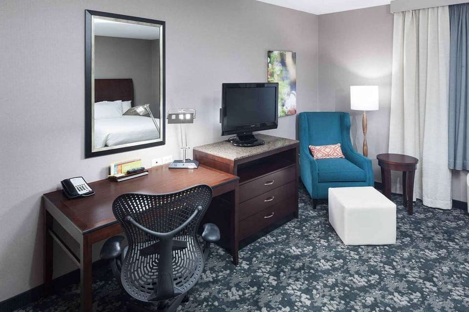 Guest room with desk, TV, chair, and soft lighting