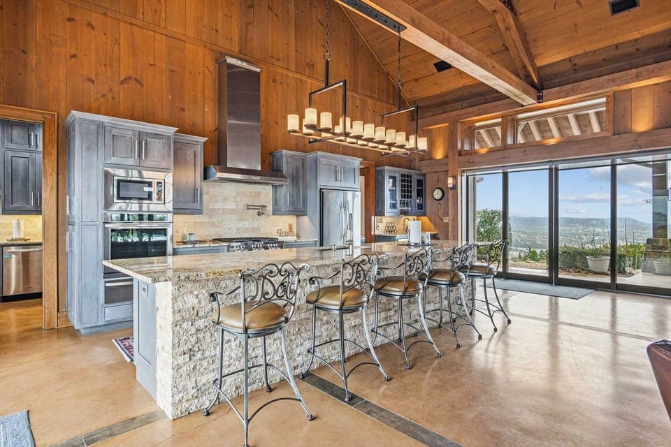 A beautifully designed gourmet kitchen featuring vaulted wood ceilings, custom cabinetry, and a spacious granite island with bar seating-perfect for gathering and entertaining.