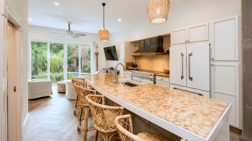 Your gourmet kitchen blends tropical elegance with modern convenience. Woven pendant lights cast warm glows over marble counters where you'll create memorable meals...