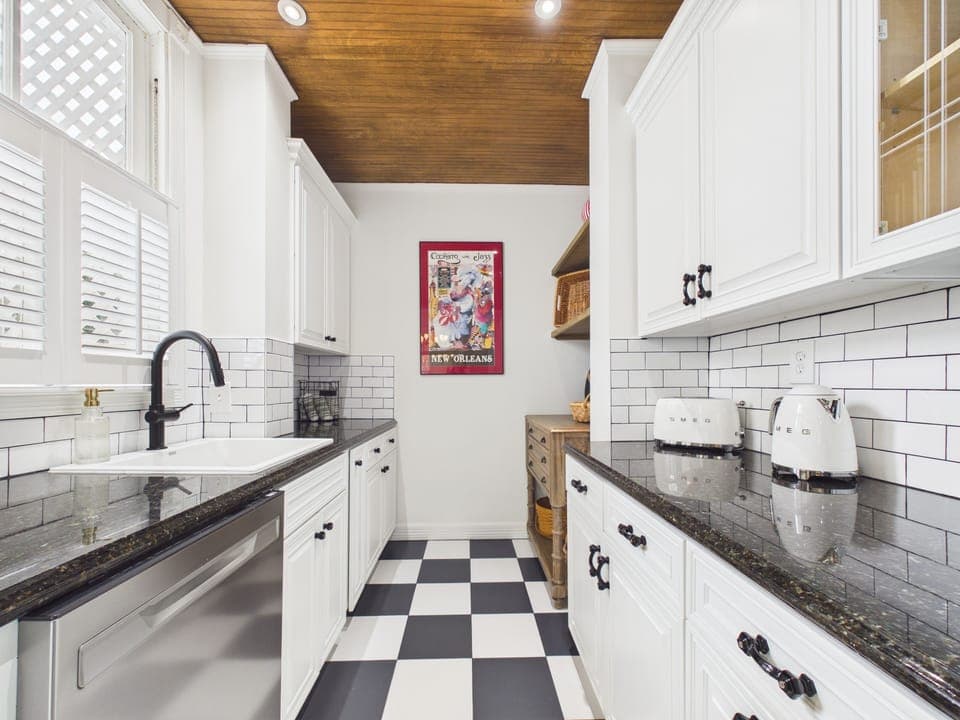 A bright galley kitchen where mornings begin with sunlight and evenings unfold over shared meals. With warm wood ceilings, classic details, and a timeless checkerboard floor, this space invites cooking, gathering, and savoring every moment together.