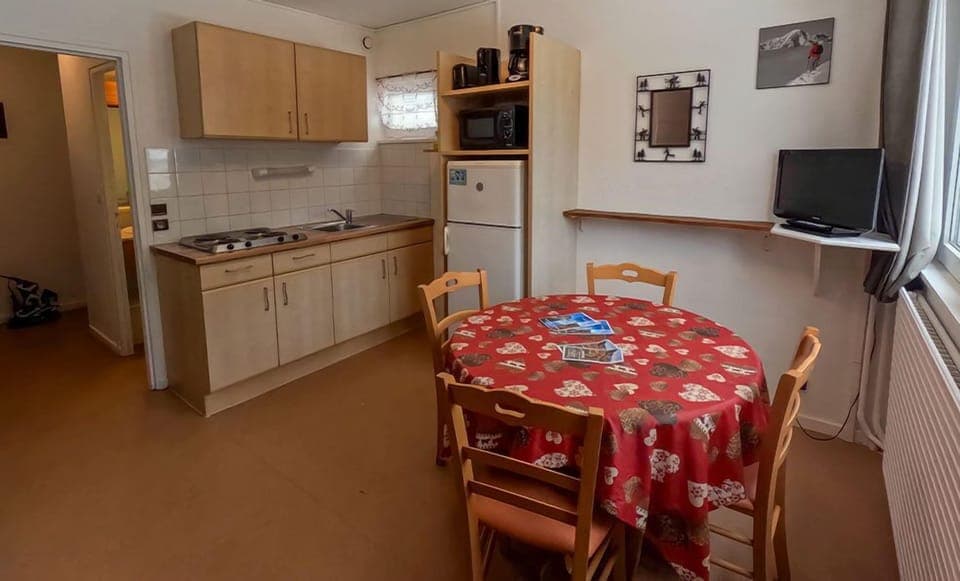 The cozy kitchenette features a red tablecloth and a well-equipped space for meal preparation, bringing a warm atmosphere to the apartment.