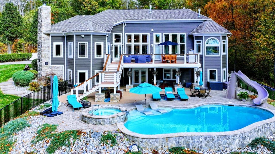 Resort-style pool + built-in spa with baja shelves, loungers in the water, and full lake views.