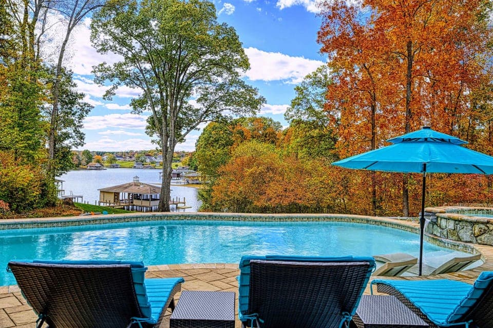 Resort-style pool + built-in spa with baja shelves, loungers in the water, and full lake views.