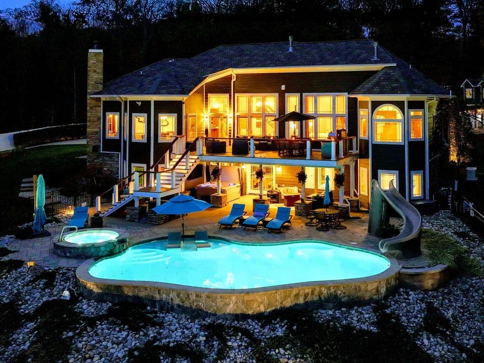 Resort-style pool + built-in spa with baja shelves, loungers in the water, and full lake views.
