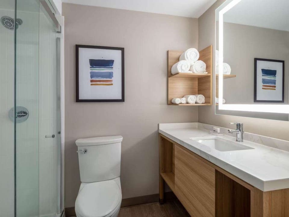 Clean bathroom with walk-in shower, vanity, mirror, and towels