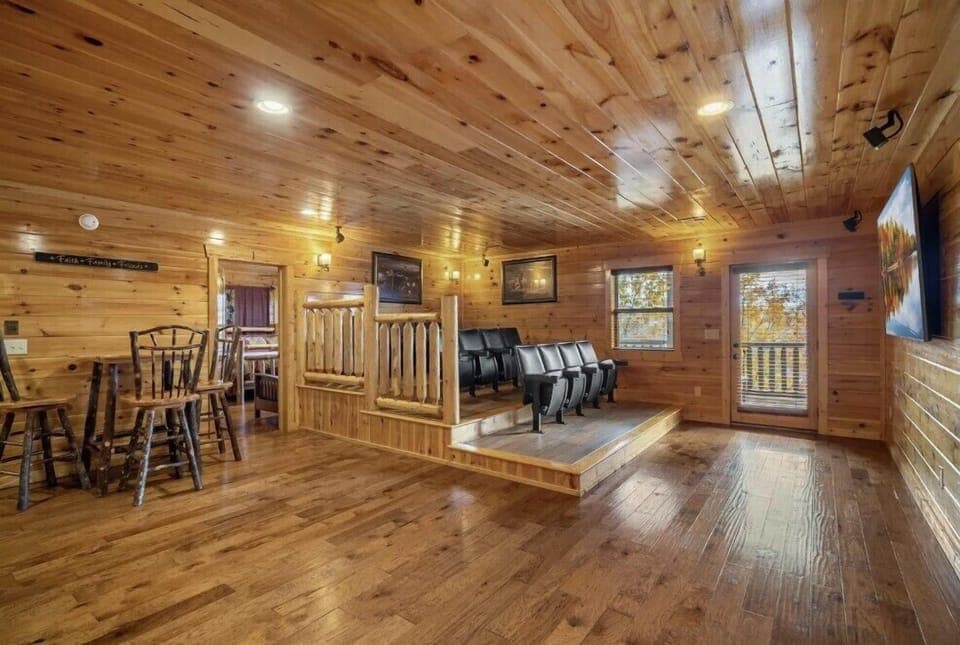 A private lodge theater room featuring tiered seating and a warm wood interior. Perfect for movie nights, game-day watch parties, and unwinding together in a cozy, rustic setting.