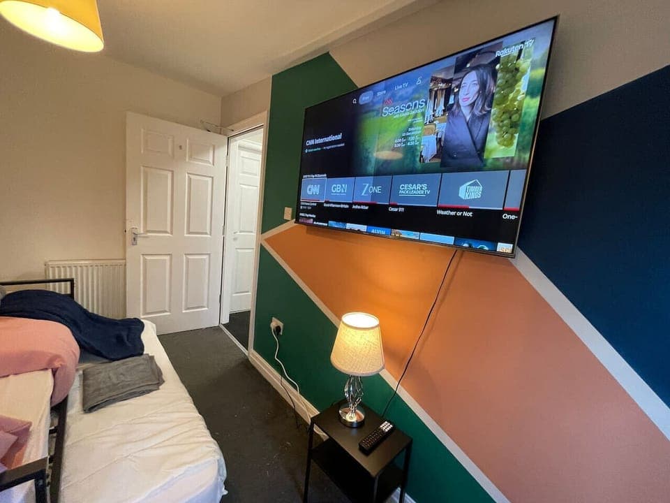 The single bedroom is shown with a wall-mounted TV above a bedside lamp.