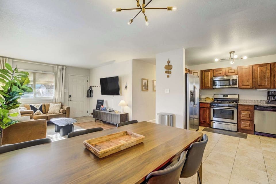 The dining area serves as a natural bridge between the kitchen and living room. Potted greenery and modern fixtures enhance the bright, open layout, providing an inviting space for family meals and conversation.
