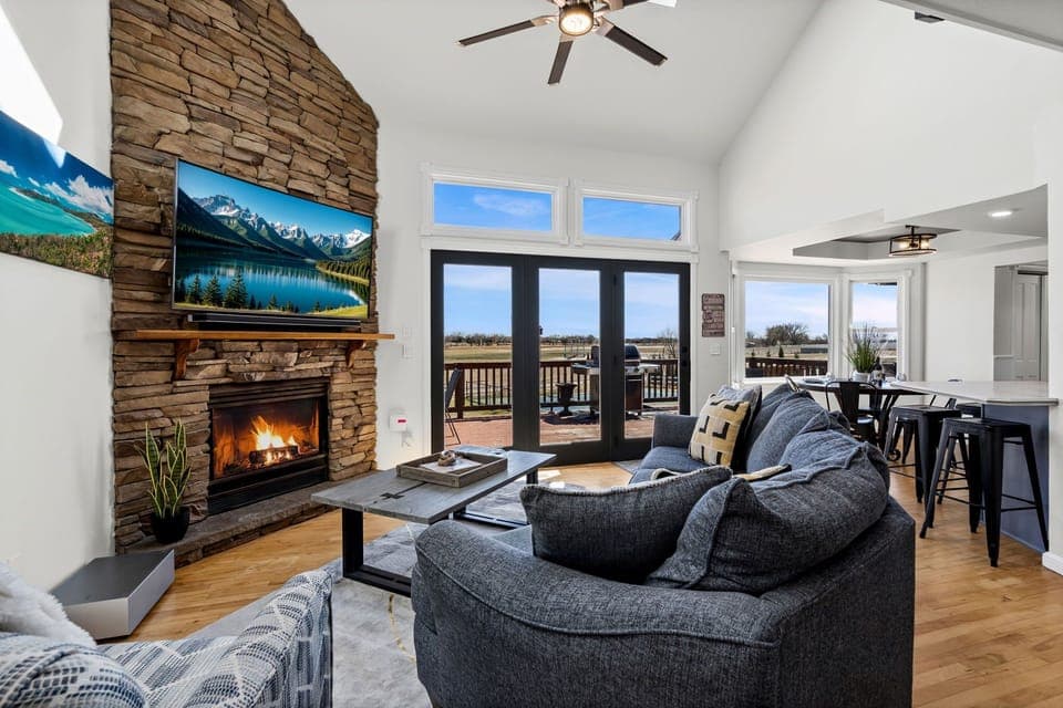 Cozy up by the crackling stone fireplace while mountain views frame your peaceful retreat through expansive windows.