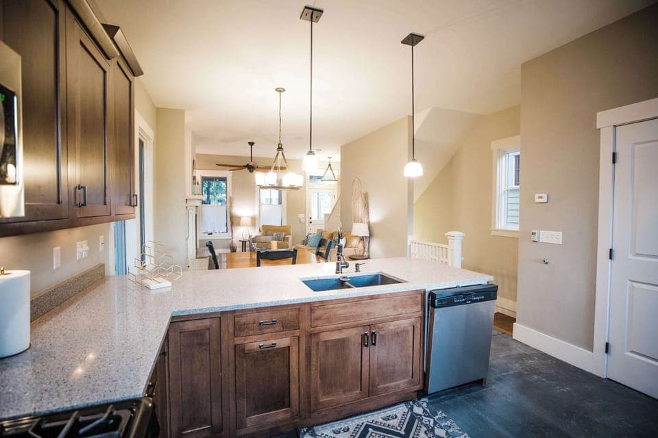 The kitchen features an oversized island with bar seating for four, warm wood cabinetry, pendant lighting, and professional-grade appliances within an open layout ideal for group meals.