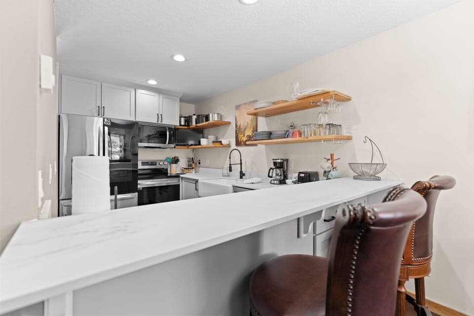 Full kitchen featuring stainless steel appliances, TV, and breakfast bar.