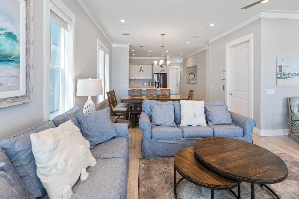 Sink into plush blue sofas in your bright open-plan living space, where coastal artwork and natural light create the perfect beach house atmosphere.