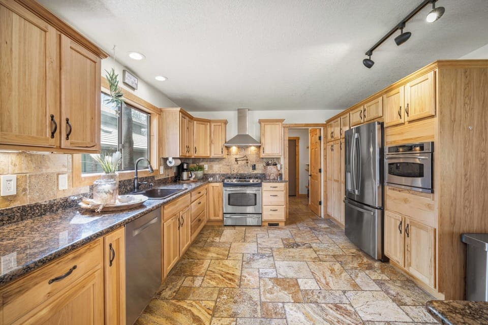 Your spacious gourmet kitchen invites culinary adventures with granite counters, stainless appliances, and warm wood cabinetry creating the perfect gathering space.