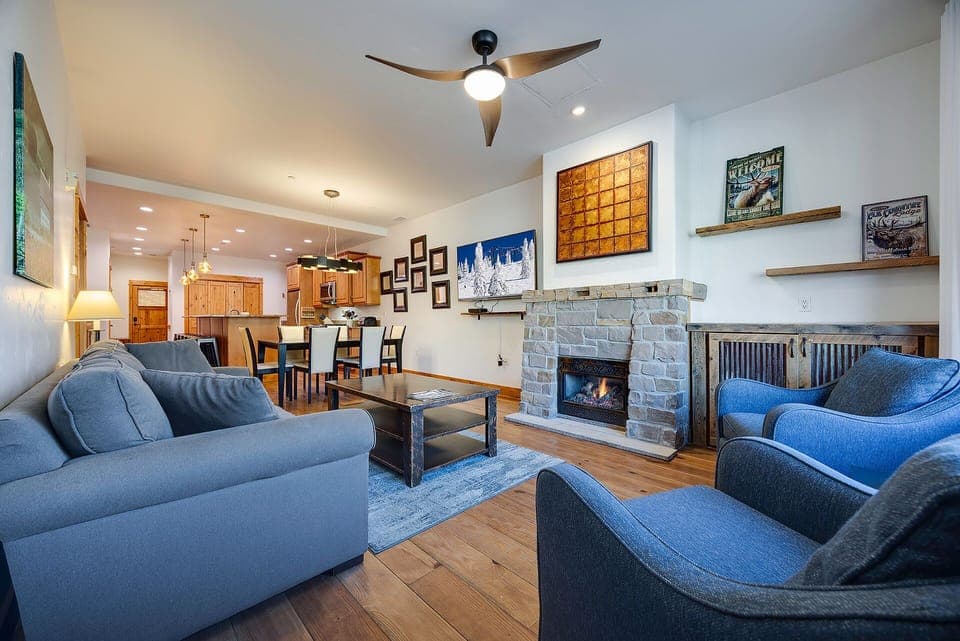 Sink into plush blue sofas beside your crackling stone fireplace, while the open kitchen invites culinary adventures in this stylish retreat.