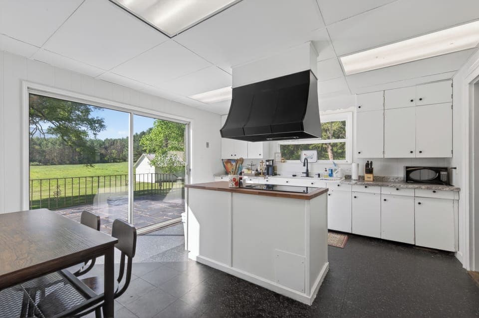 Sunny kitchen with large windows and outdoor views.