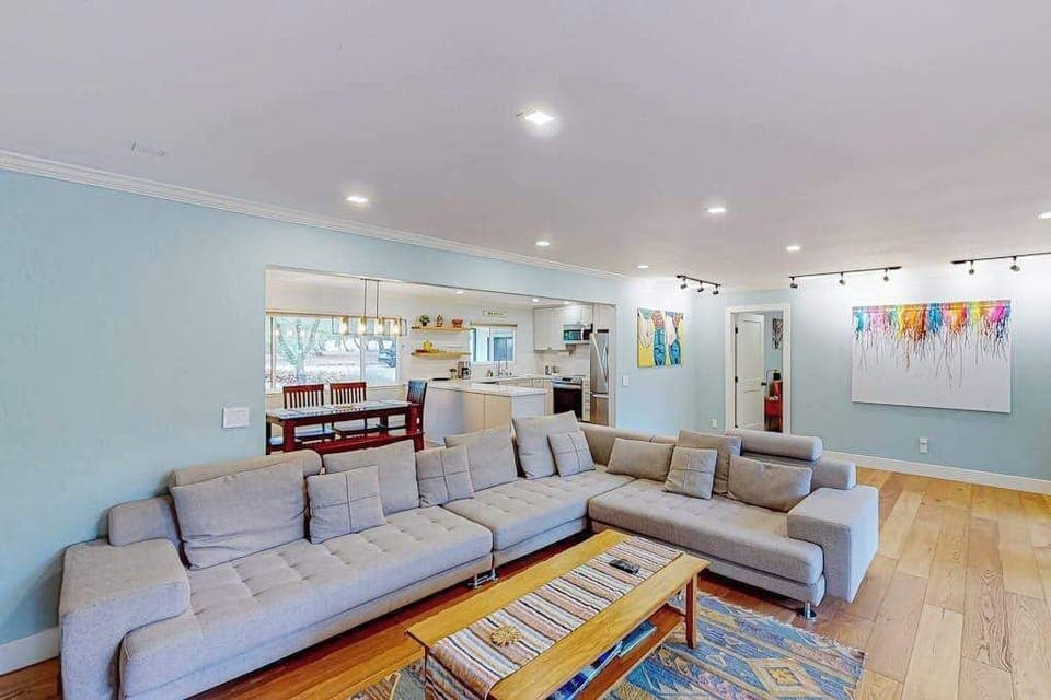 Bright, airy, and art-filled — your open-concept living space flows seamlessly into the kitchen, with track lighting highlighting curated artwork perfect for a wine country vibe.