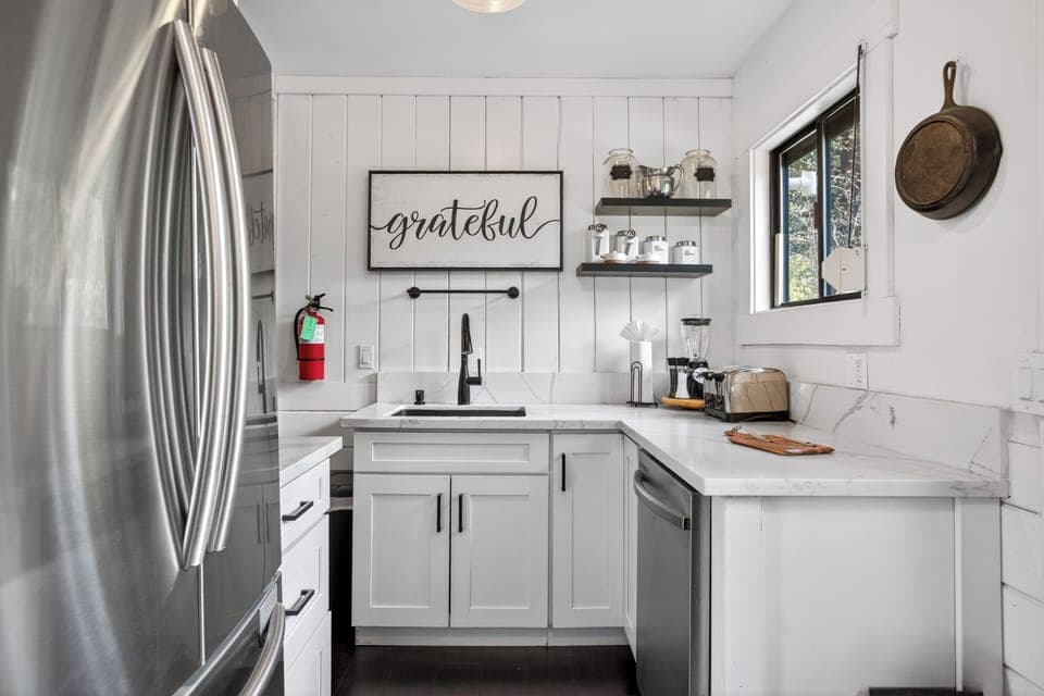 Bright and modern culinary space featuring white cabinetry and stainless steel accents.