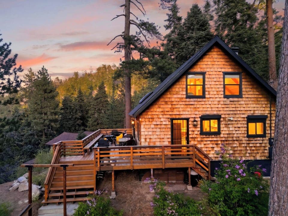 Stunning mountain architecture featuring classic cedar shingles and a spacious outdoor living area nestled in the forest.