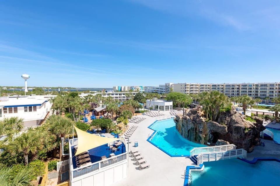 Dive into a resort pool framed by palms and rocks.