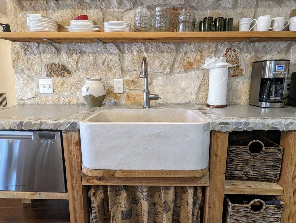 Limestone wall kitchen with marble sink and custom stone/pebble countertop.