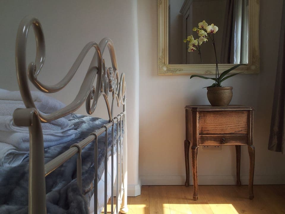 Sunny romantic bedroom with oak floors and a Laura Ashley king size bed