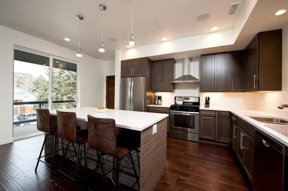Kitchen with traditional drip coffee maker, fridge, stove, and oven. Island with bar stools.