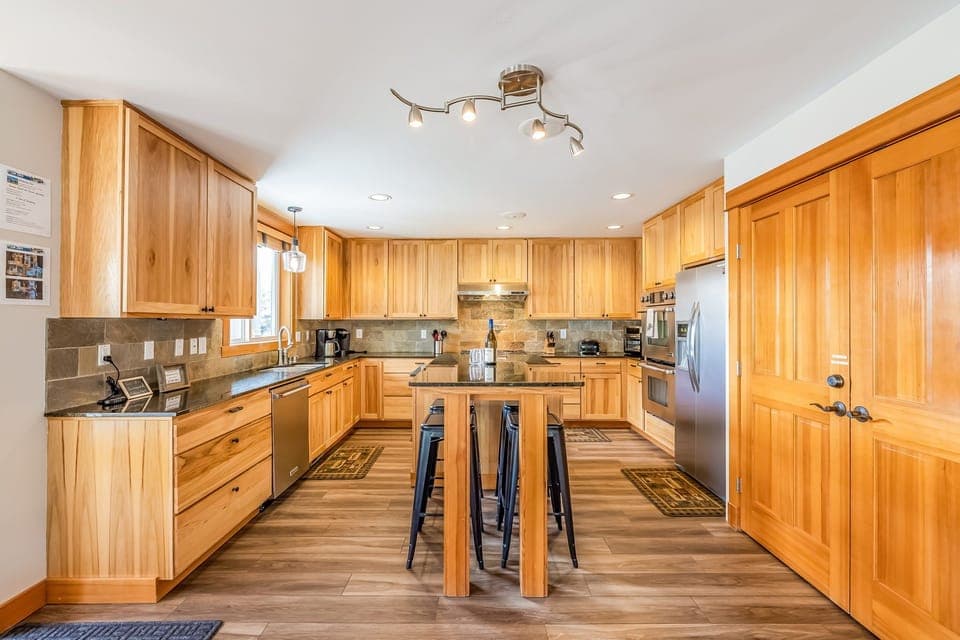 Chef's Kitchen w/ 6 Burner Gas Cook Top, Wall Ovens, and 4 Seating Center Counter Table