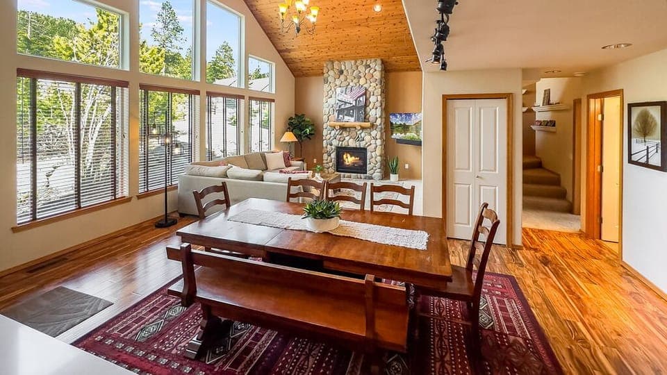 Vaulted great room with stone fireplace, lodge-style dining.
