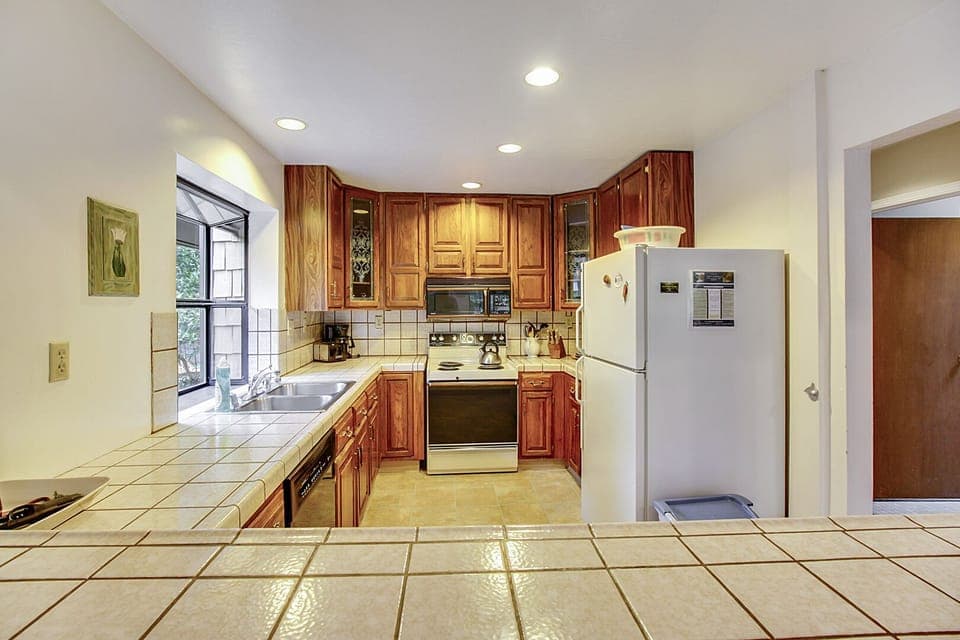 Fully stocked kitchen, tile counters, and convenient pass through to the dining area.