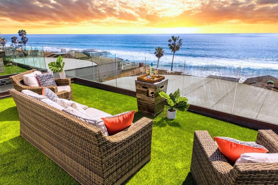 Spectacular oceanfront terrace captures golden sunsets over endless blue waters, with palm trees dotting the pristine coastline below.