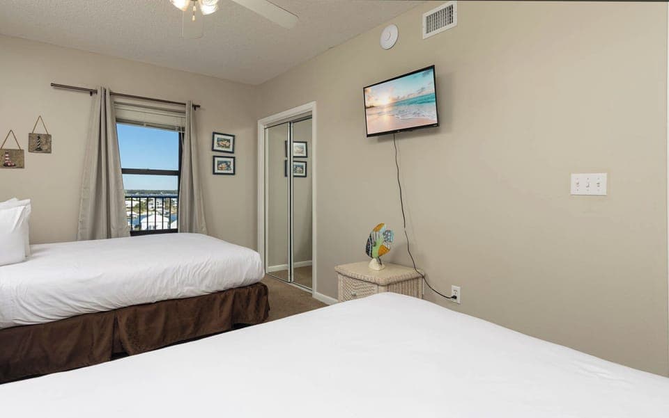 Inviting guest bedroom with two queen beds, a TV for entertainment, and a window offering a lovely view
