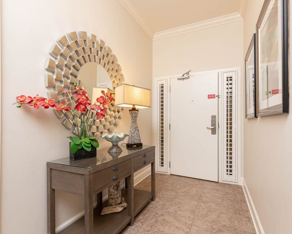 This welcoming entryway features a stylish console table, floral decor, and a decorative mirror, setting a cheerful tone