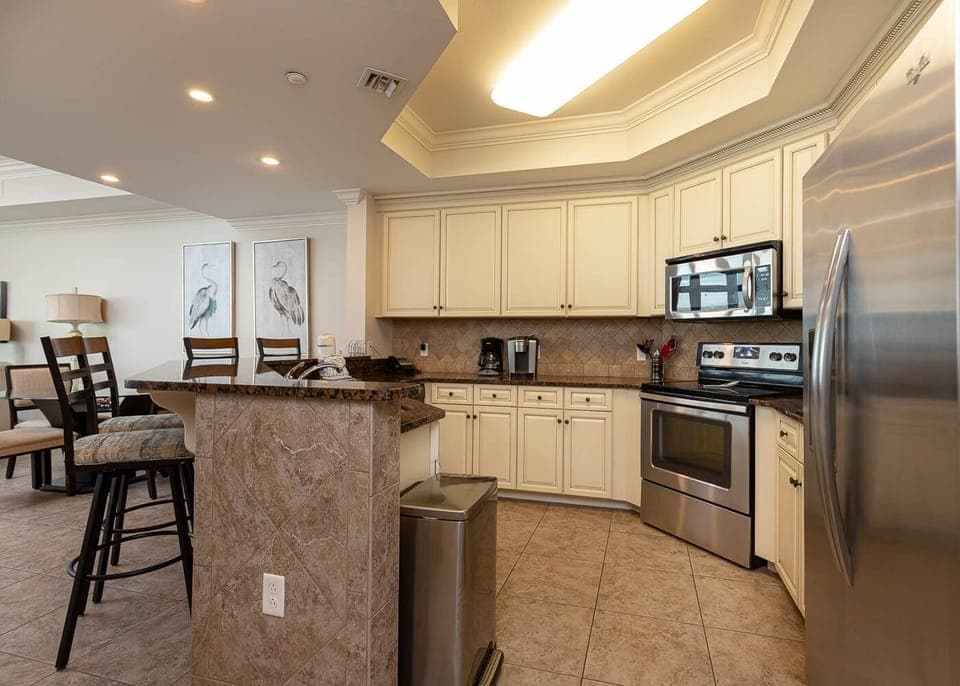 The kitchen features stainless appliances, granite countertops, and a cozy bar area, with a Keurig and a coffee maker