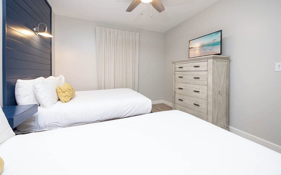 Inviting guest bedroom featuring two comfortable double beds, a stylish dresser, TV, and soft lighting