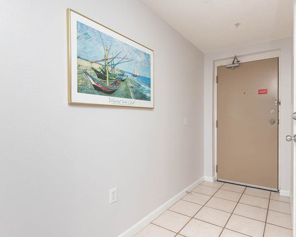 Step into a welcoming entryway adorned with coastal artwork and tiled flooring, setting a relaxed tone for your stay