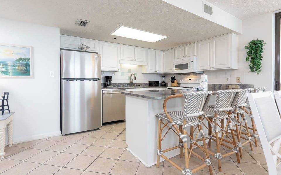 White cabinetry and a sleek breakfast bar complement the modern kitchen, featuring stylish bar stools for casual dining