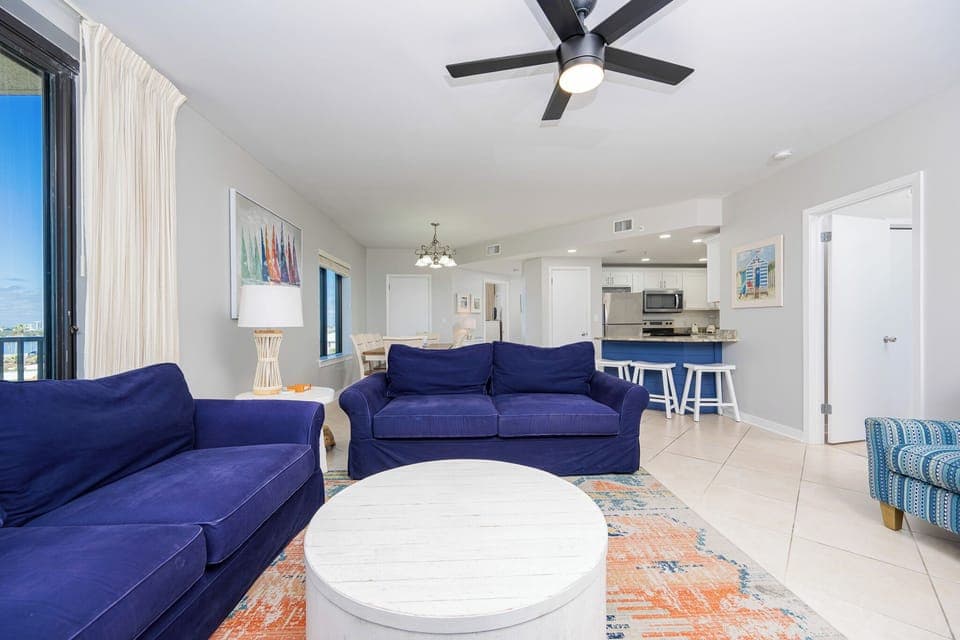 Relax on the deep blue sofas surrounded by vibrant decor and a bright, open layout leading to the dining area