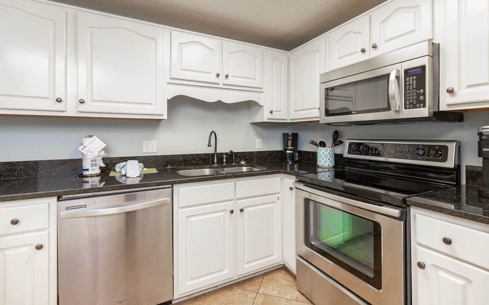 Prepare meals in the stylish kitchen, featuring stainless appliances, ample counter space, and white cabinetry
