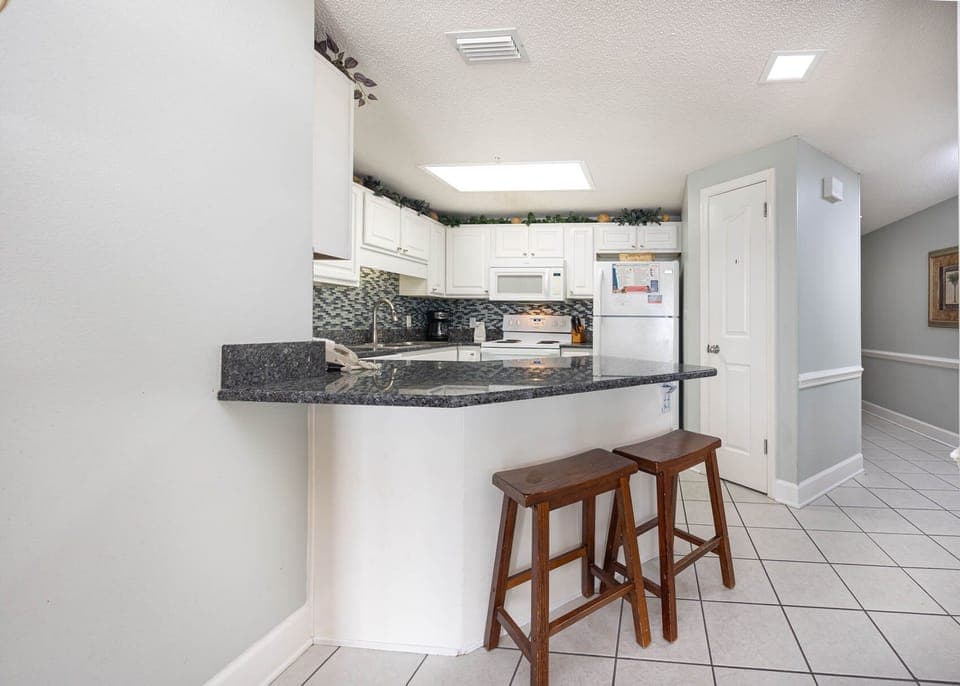 Enjoy casual meals at the breakfast bar, featuring sleek countertops and a view into the bright kitchen space