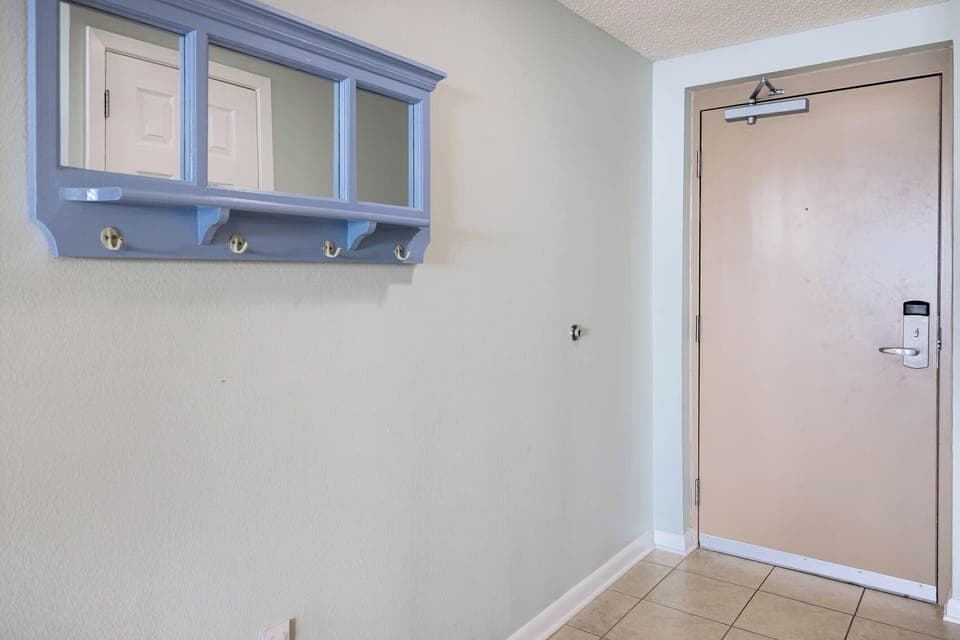 Step into a welcoming entryway featuring a blue coat rack and a mirror, perfect for a quick glance before heading out